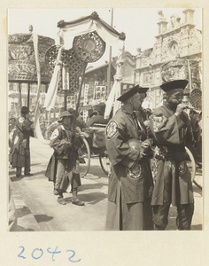 Members of a wedding procession carring umbrella, fan-shaped screen, draped mirror, and musical instruments