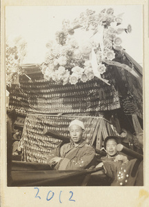 Coffin-bearers carrying draped coffin with wreaths of paper flowers during funeral procession