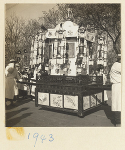 Members of a funeral procession carrying a litter decorated with lanterns and fringed banners