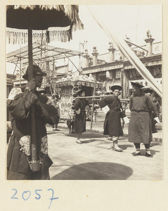 Members of a wedding procession carrying umbrella and sedan chair