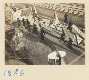 Funeral procession with inscribed banners and umbrellas