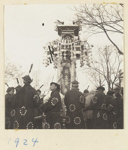 Members of a funeral procession carrying a paper structure containing soul tablet and portrait of the deceased