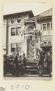 Members of a funeral procession carrying a paper structure containing soul tablet and portrait of the deceased