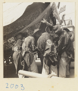 Coffin-bearers lifting coffin off the ground in a funeral procession