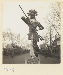 Paper figure armed with a trident being carried in a funeral procession