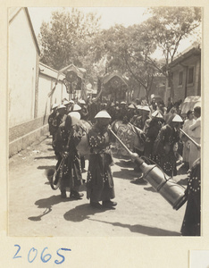 Members of a wedding procession playing musical instruments and carrying draped mirrors and fan-shaped screens