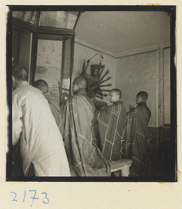 Monks with gong, painting, and multi-armed statue inside temple on Miaofeng Mountain