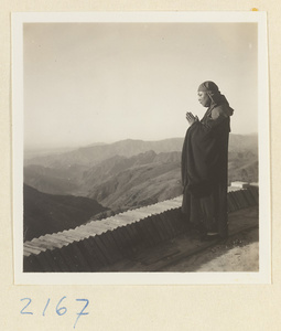 Pilgrim praying on Miaofeng Mountain with mountain landscape in background