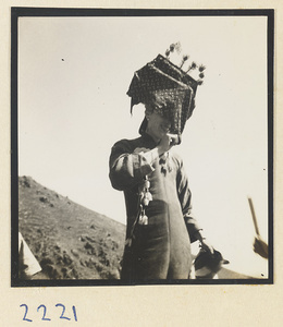 Pilgrim wearing a hat decorated with souvenirs on the trail up Miaofeng Mountain