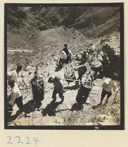 Pilgrims carrying temple society boxes decorated with flags and bells on the trail up Miaofeng Mountain