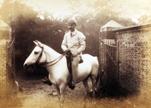 Herbert Wilcockson on a white horse by the entrance to a house, Shanghai