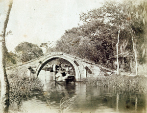 A boat going under a small bridge in a rural area