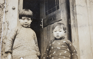 Two children by a house front door