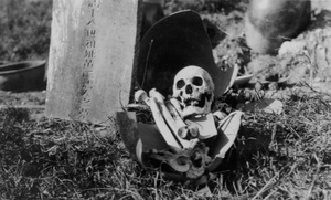 A broken open grave pot and gravestone