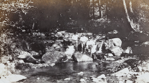Three men standing on rocks by a stream