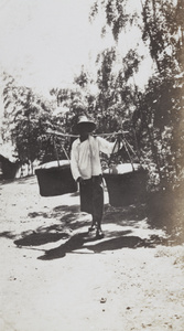 Pedlar carrying two covered baskets