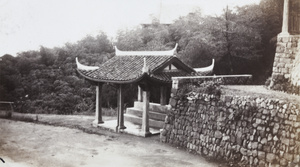 Resting place with a curved roof, next to a bungalow in the same style