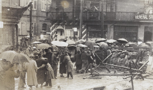 Police searching people at a street barricade in heavy rain, Shanghai