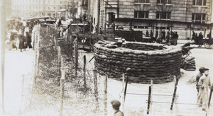 Circular sandbagged guard post and barbed wire barricade at a road junction, Shanghai