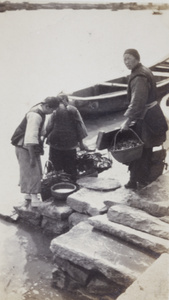 Three women with baskets on embankment steps