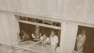 Women looking up to passengers and holding streamers from a departing ship