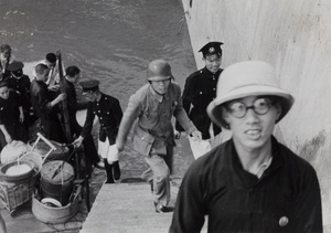 A Chinese soldier and Shanghai policemen unloading containers (likely food) from a boat, Shanghai, 1937