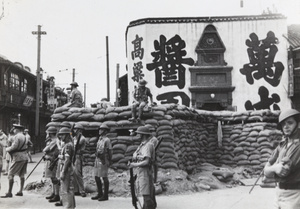 British soldiers at a sandbagged guard post watching fire fighters, Shanghai, 12 September 1937