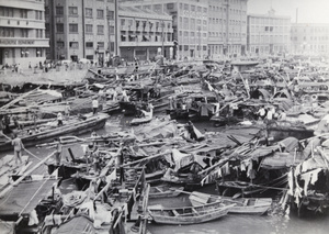 Shanghai Municipal Policeman in a water taxi amidst barges and sampans, Soochow Creek, Shanghai, 1937