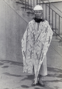 Man wearing a women's hat and a length of patterned fabric, Shanghai, 1937