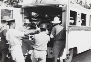International Red Cross volunteers placing casualty in ambulance, Shanghai, 1937