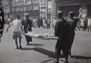 Volunteers stretcher bearing a person injured in bombing of Sincere Company department store, Shanghai, August 1937