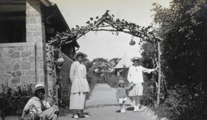 Woman and three girls pose by a pergola with gourds