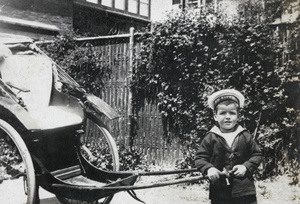 Boy dressed in sailor suit (HMS Suffolk) posed with rickshaw