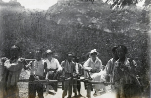 Chinese bearers carrying two women in sedan chairs