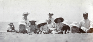 Mothers and pith helmeted children, with amah, on a beach