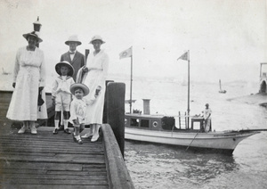 Family group on pier, with steam launch