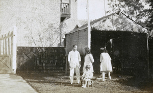 Amah, Gerald Johns, with Doreen and Olivia Symons in a garden with a matshed
