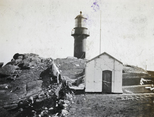 Lighthouse, with damaged building and wall