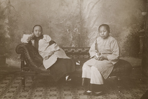 Studio portrait of a woman, with a young woman holding a water pipe