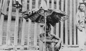 Man smoking pipe under tattered umbrella