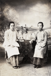 Studio portrait of two women with a vase, books and fans