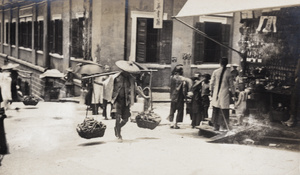 A porter carrying a heavy load up a street, Hong Kong