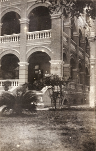 A couple standing on a veranda of a large building