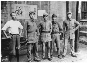 Staff of sub-district Headquarters (Xiao Fang on the left) in front of a wall with posters, Central Hebei province