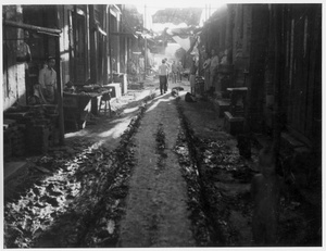 A muddy street and makeshift roadside stalls, 1938