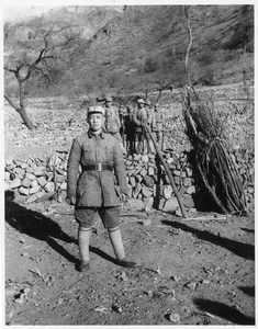 A soldier near a bundle of firewood and a  group of soldiers