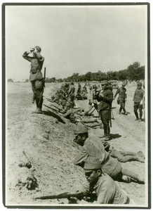 Officers with binoculars and soldiers behind a bank