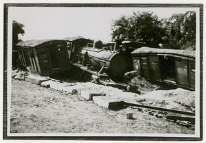 A derailed locomotive and damaged train carriages