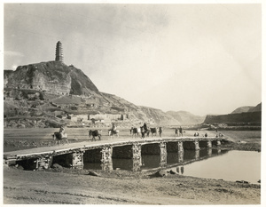 A caravan of mules crossing a bridge made of wood and stone, Yan'an (延安)