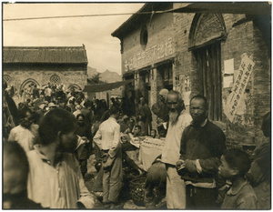 Crowded street market by a building with political slogans, South Shanxi